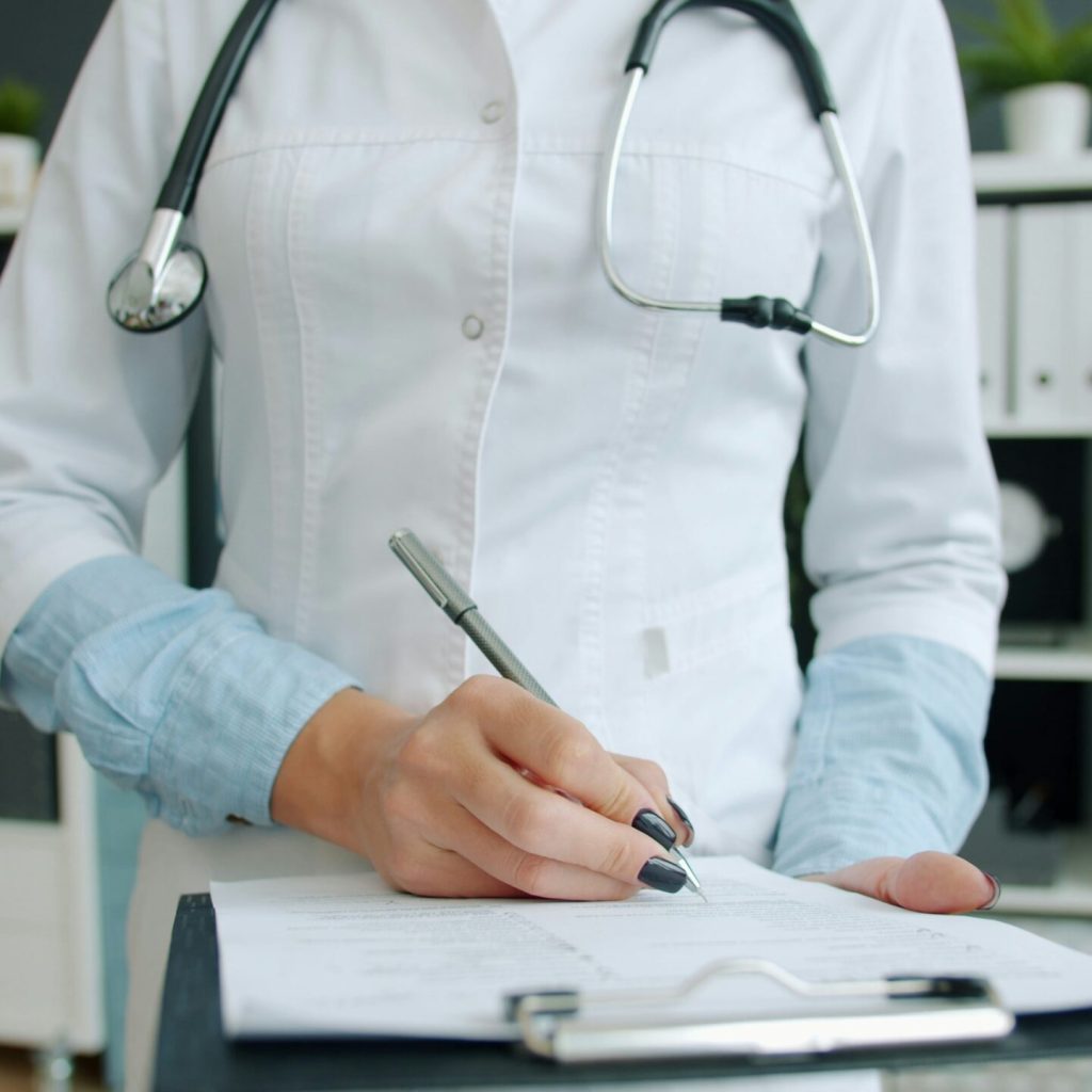 healthcare provider writing notes on a pad
