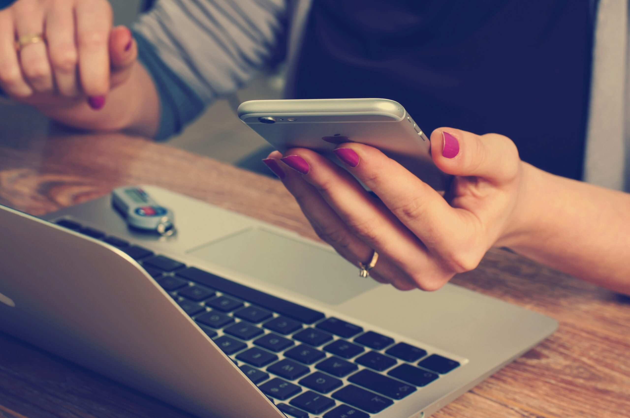woman holding phone and using computer